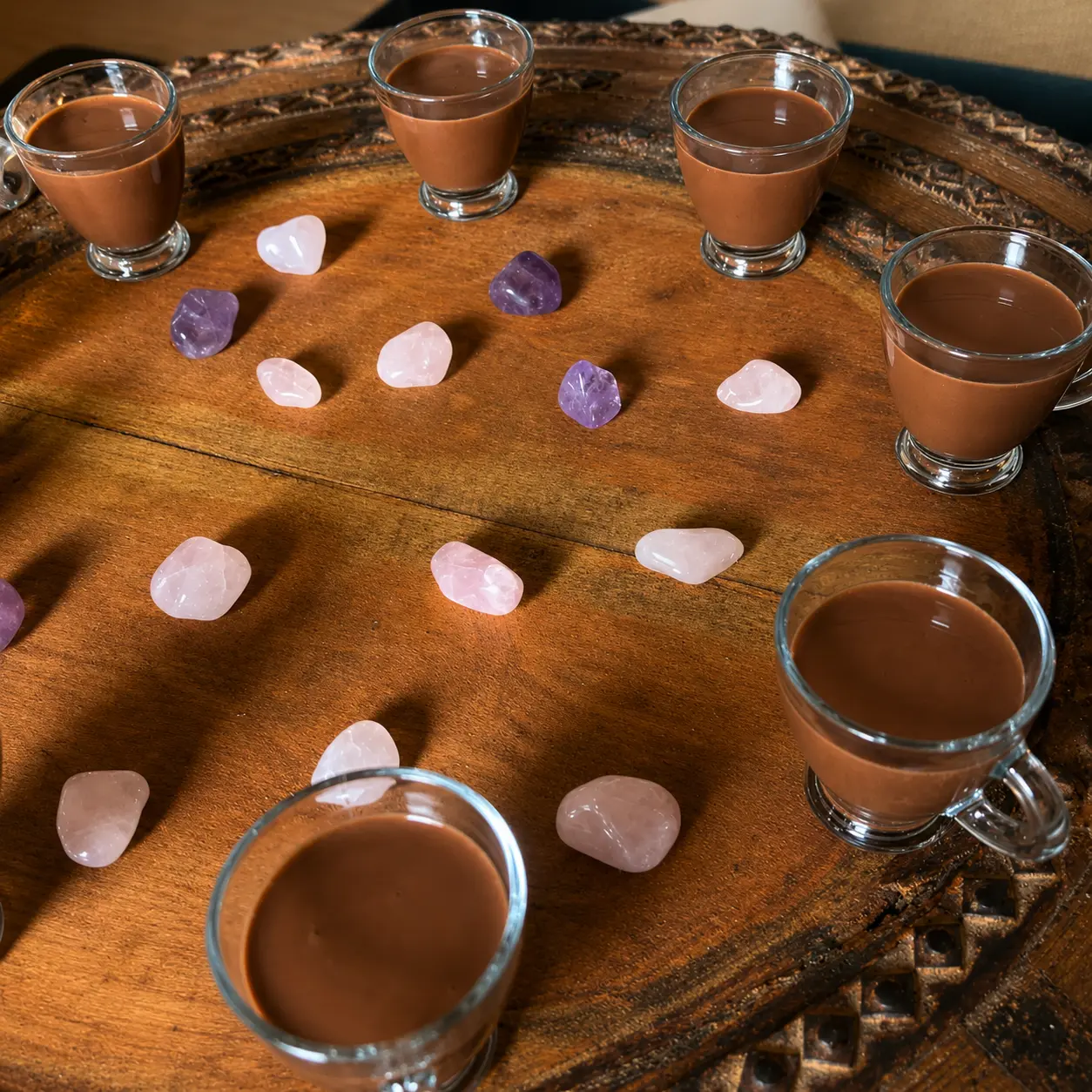 Cacao served on a wooden tray with rose quartz and amethyst stones