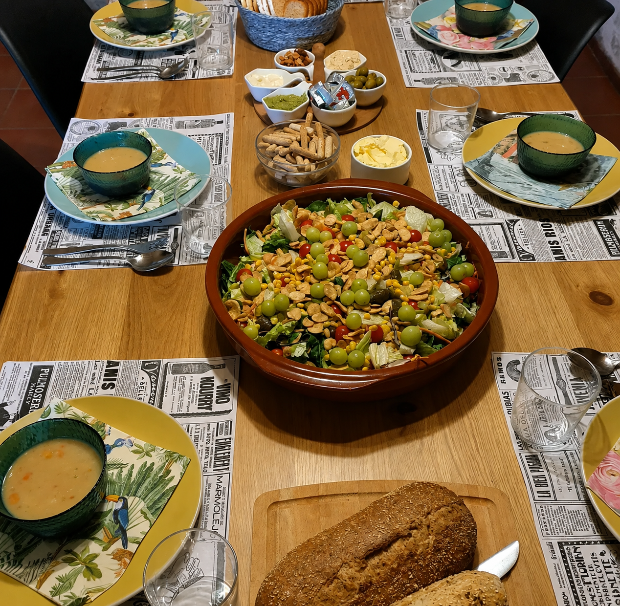 A shared table laid with soup, salad and fresh bread