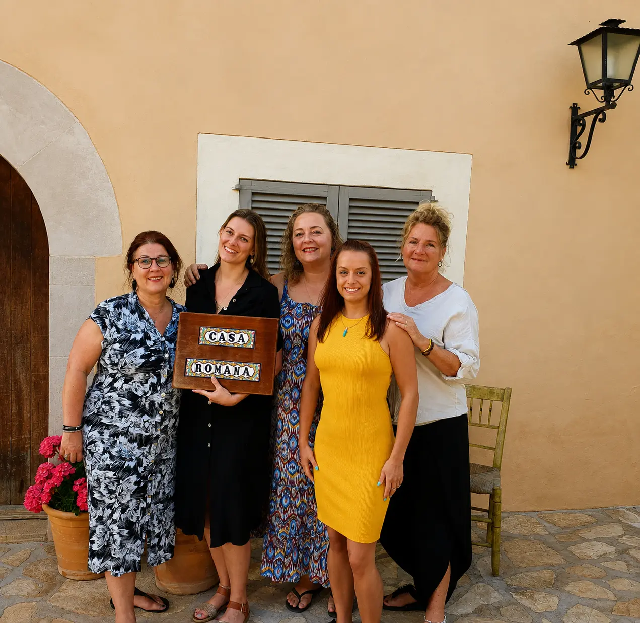 A group standing together at Casa Romana holding the house sign
